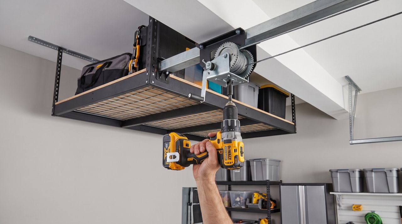 Cordless power drill operating the drive winch of a lowering garage ceiling storage rack